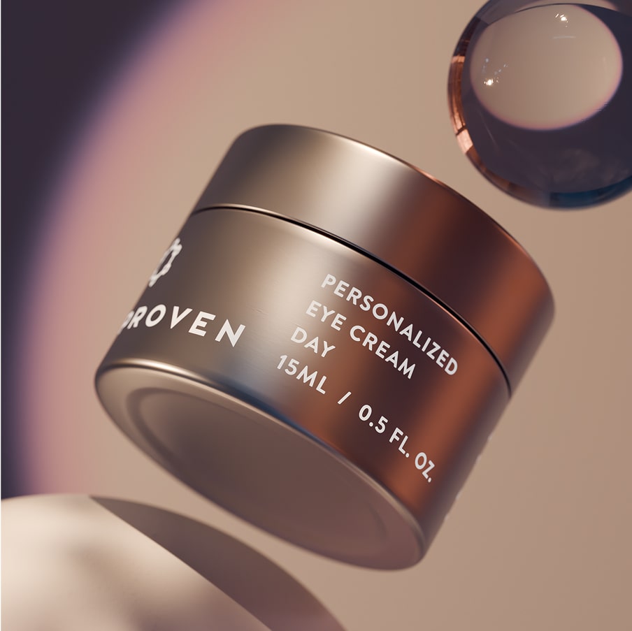 The Personalized Eye Cream Day jar, 15 ml, in warm bronze on a peach-toned set beside a glass sphere.