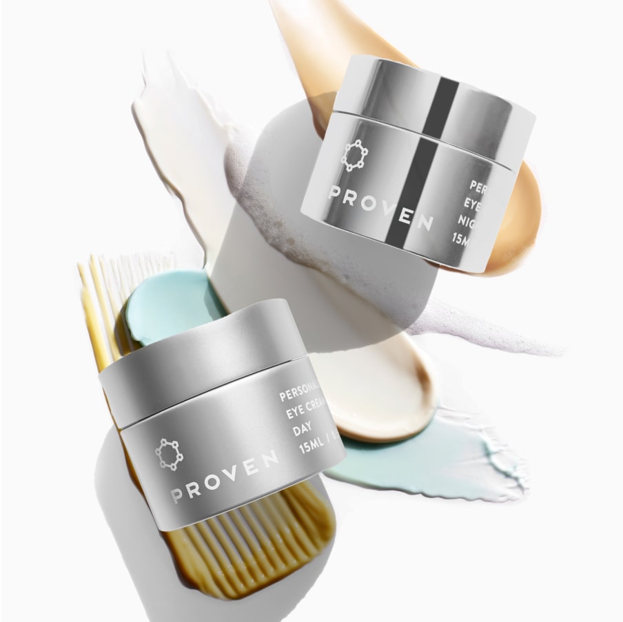 The Day and Night eye cream jars together on a pale plinth, cream and gold swatches around them.