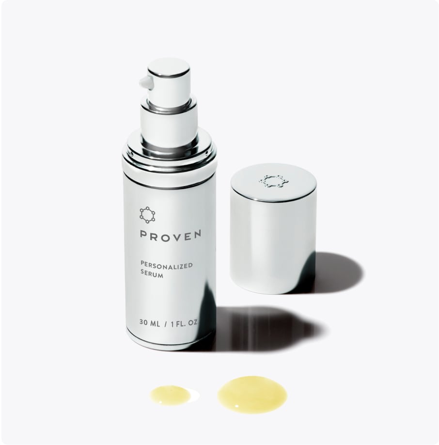 The Personalized Serum bottle with its cap off beside it and two golden drops in front.