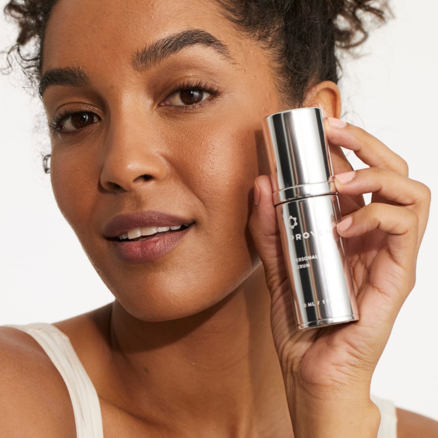 A woman holding the Personalized Serum bottle beside her face.