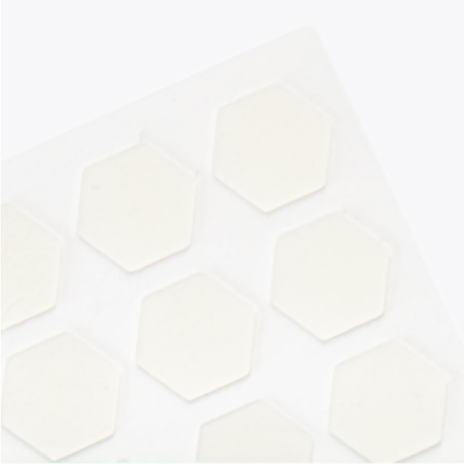 A close-up of the hexagonal patches on their backing sheet, showing how thin and near-clear they are.