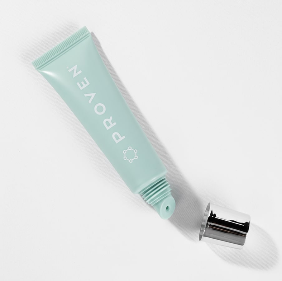 The lip balm tube lying on its side with the silver cap unscrewed beside it.