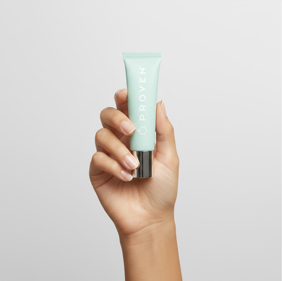 A hand holding the lip balm upright, showing its travel size.