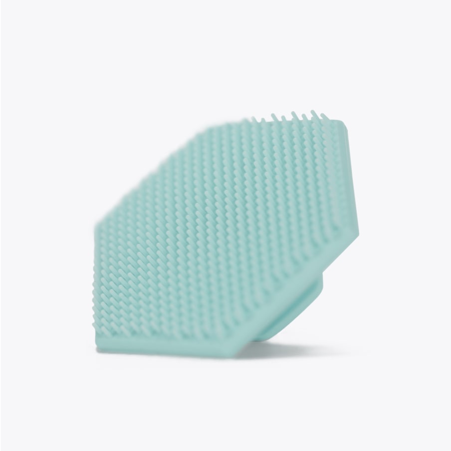 The mint green silicone pad on its own, showing the fine bristles across its face
