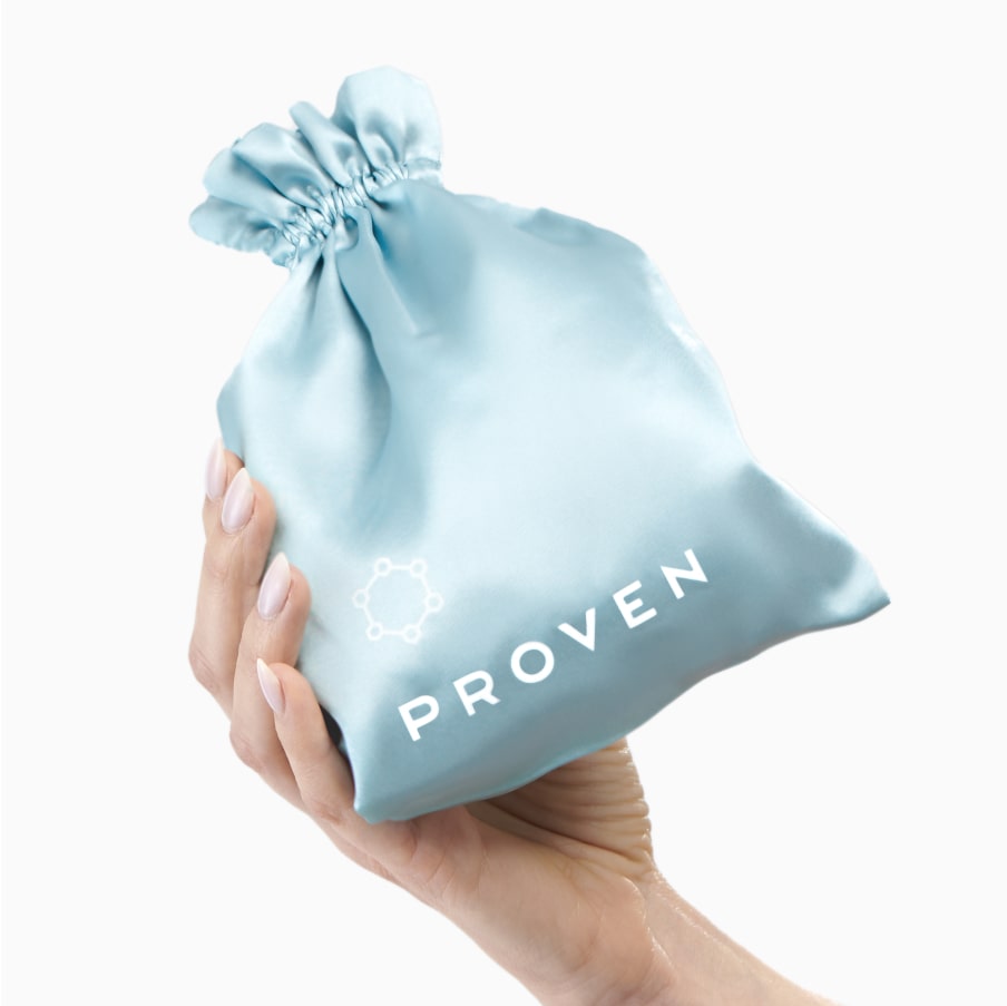A hand holding the PROVEN satin drawstring pouch the pillowcase comes in.