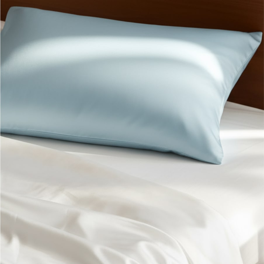 The pillowcase on a pillow against white bedding, showing its sheen.