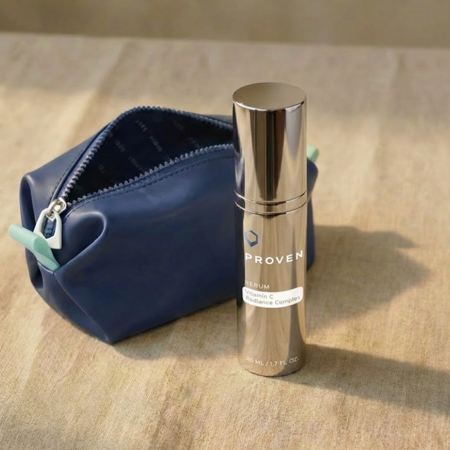 The serum bottle standing beside a navy leather toiletry pouch on a sunlit wooden table